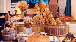 Mesa de desayuno tipo buffet con pan, bollería y una lámpara en una habitación acogedora.