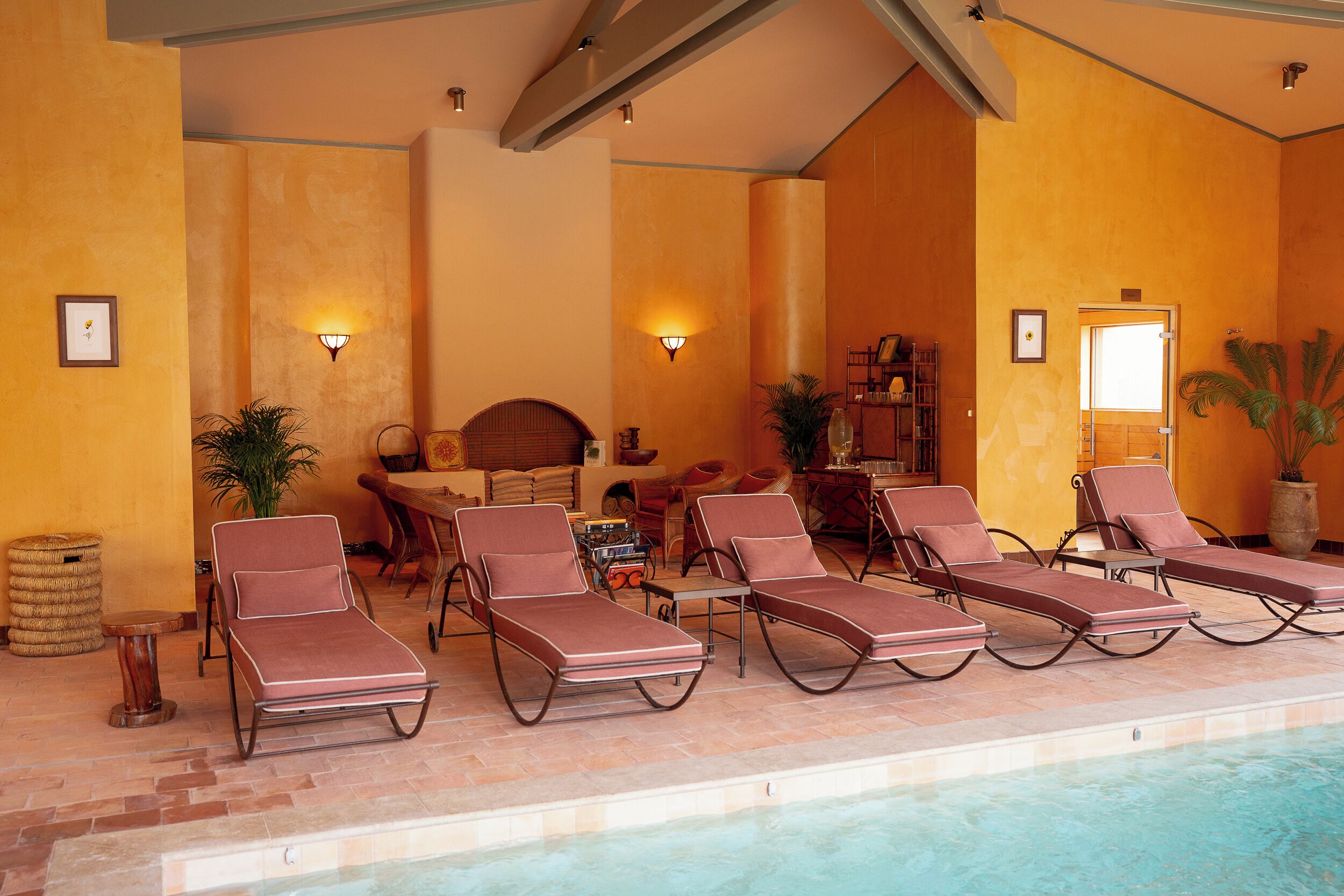 Un área junto a la piscina con sillones, una mesa y un sofá.