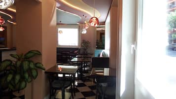 Een restaurantinterieur met een geruite vloer, moderne verlichting en uitzicht op de straat.