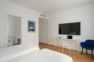 Een moderne hotelkamer met een groot bed, een bureau met een laptop, een televisie en een stoel.