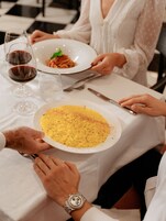 Una mesa de comedor con platos de comida, copas de vino y cubiertos.