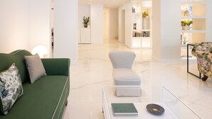 Una sala de estar moderna con un sofá verde, un sillón blanco y una mesa de centro de vidrio.