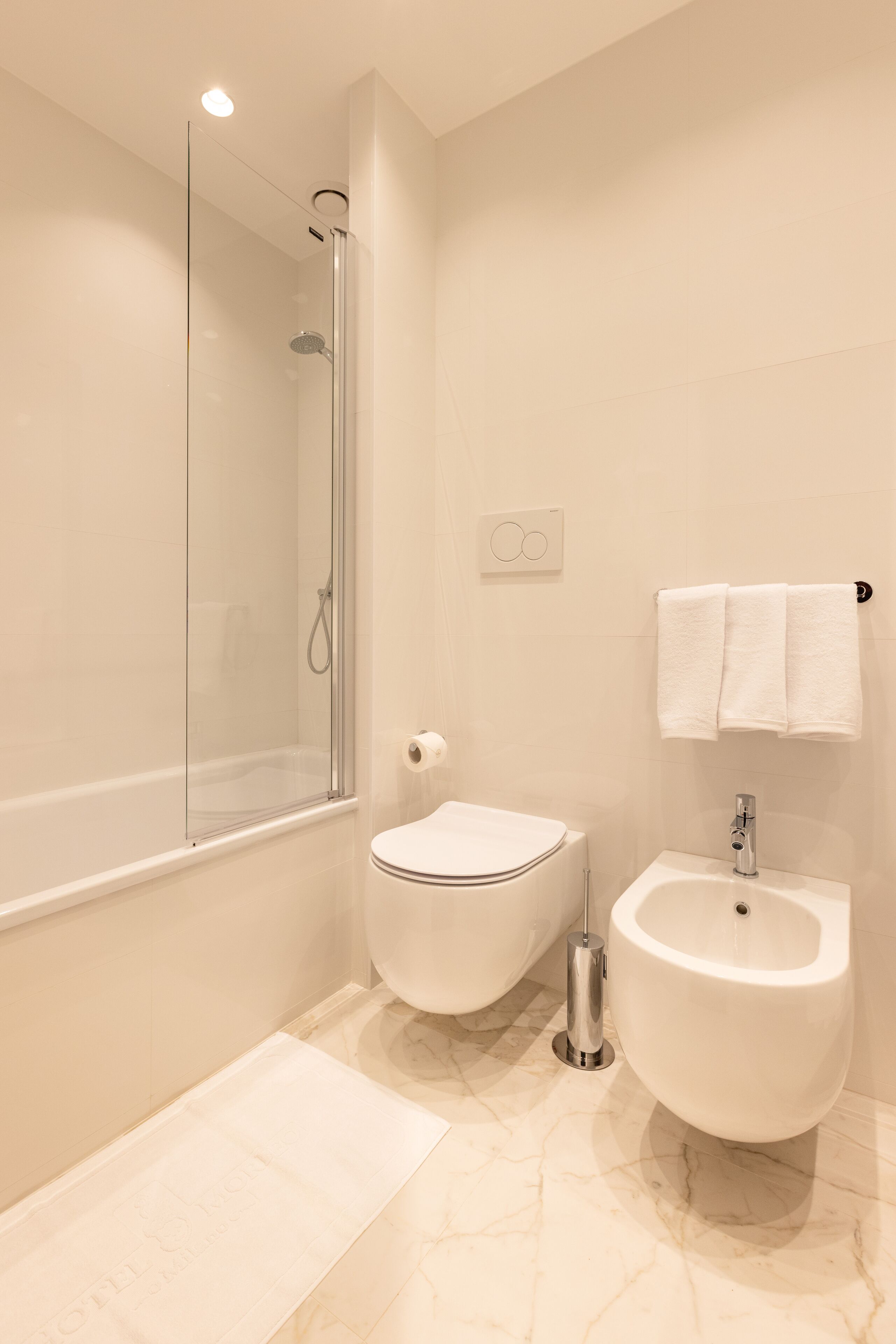 Un baño moderno con ducha envuelta en vidrio, inodoro y bidé.