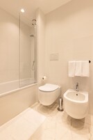 Une salle de bain moderne dotée d’une douche à parois de verre, de toilettes et d’un bidet.