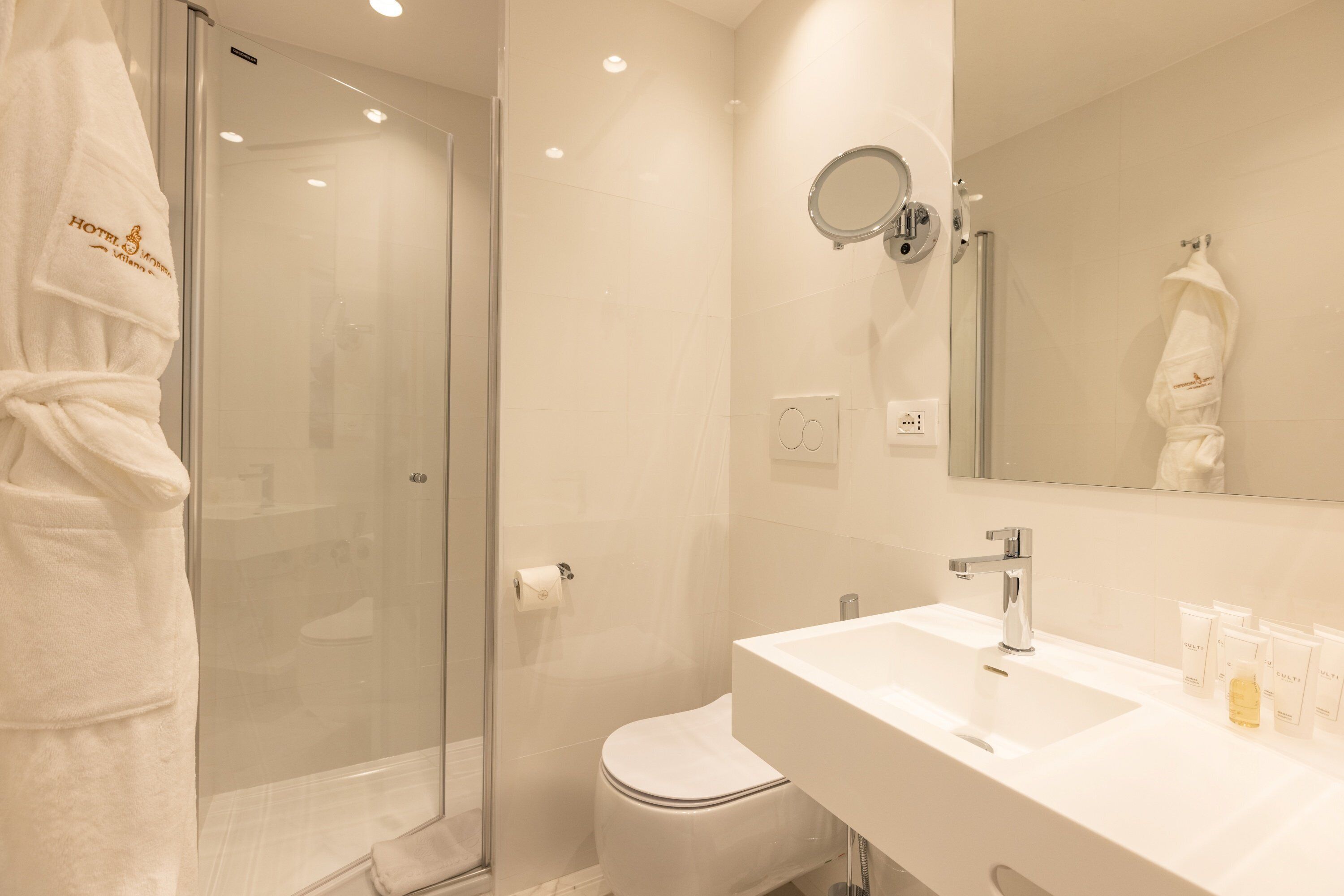 Un baño moderno con cabina de ducha de vidrio, un lavabo blanco y un espejo.