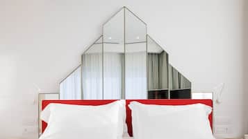 Ein Hotelzimmer mit einem Spiegelkopfteil, weißer Bettwäsche und einem roten Akzent am Kopfteil.