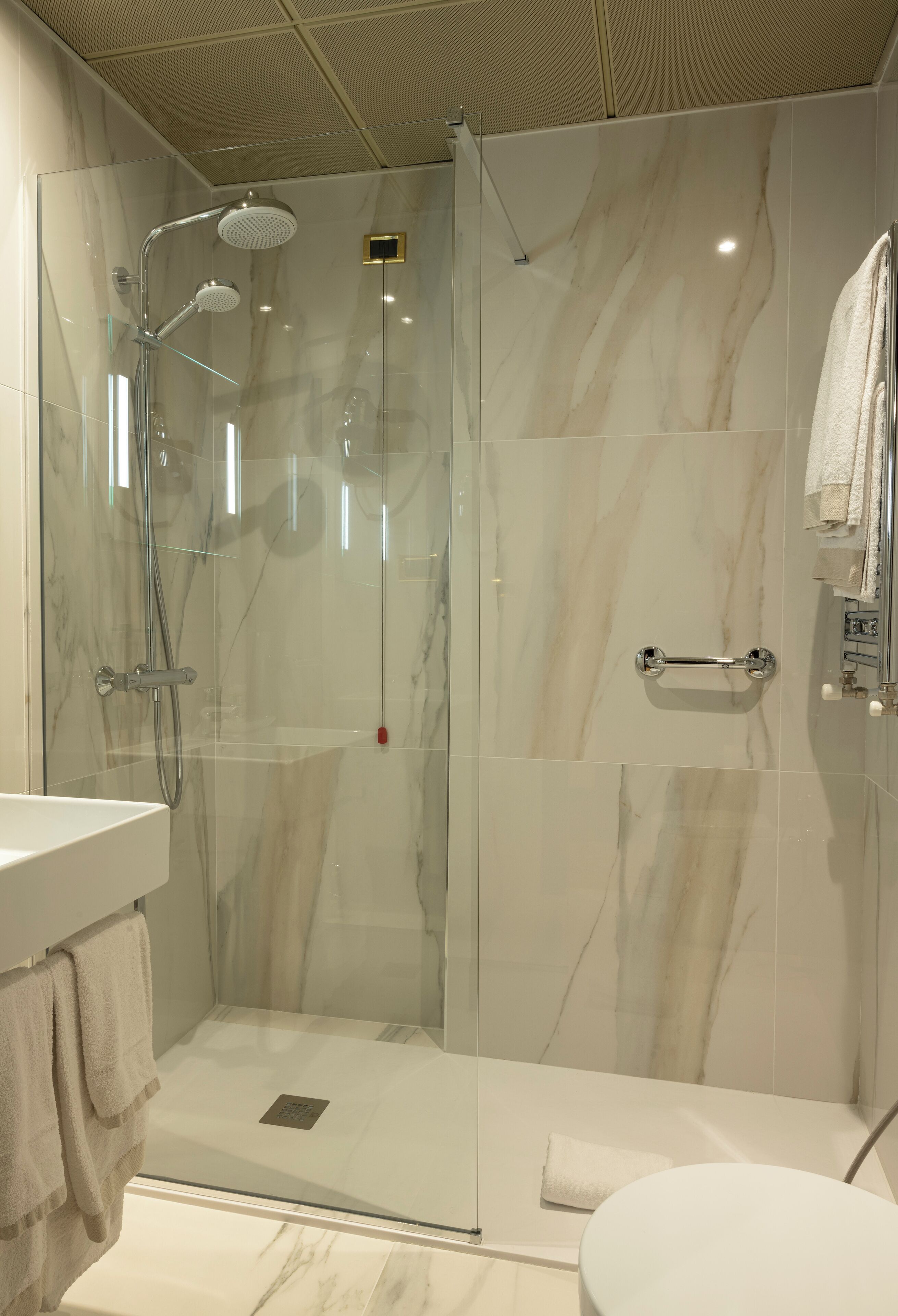 Un baño moderno con ducha de vidrio, lavamanos blanco y un inodoro.