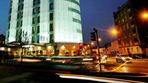 A multi-story hotel with a modern design, featuring a curved facade and illuminated windows. - c-hotels Concorde (Milan)