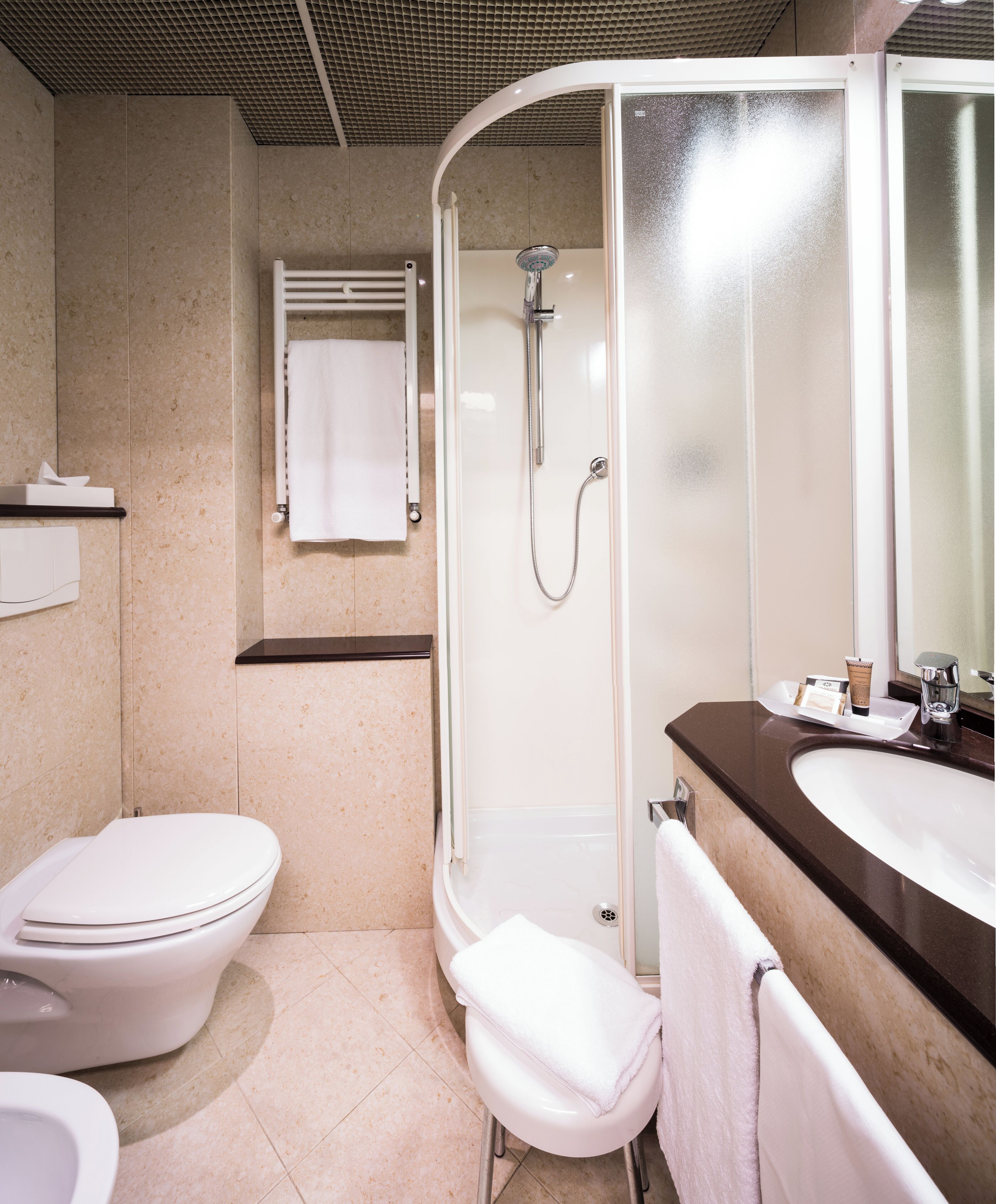 Un baño moderno con inodoro, cabina de ducha y lavamanos con espejo.