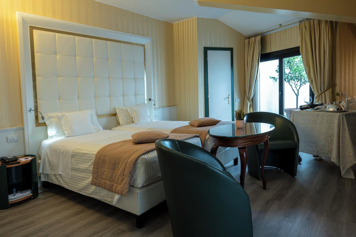 Ein Hotelzimmer mit einem großen Bett, einem runden Esstisch und zwei Stühlen.