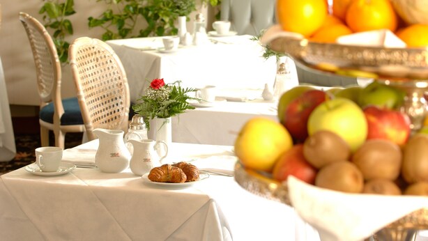 A breakfast setting with a table set for two, including croissants, fruits, and a pitcher. - c-hotels Concorde (Milan)
