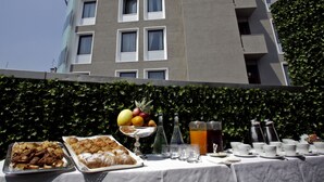 A table set outdoors with food and drinks, a building with balconies in the background. - c-hotels Concorde (Milan)