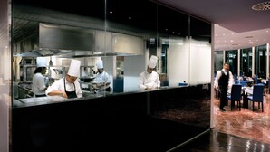 Ein modernes Restaurant mit Küchenbereich, Esstischen und einem Kellner.