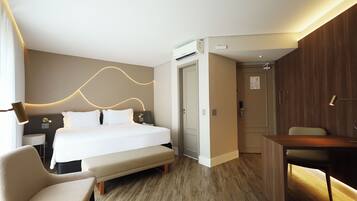 Quarto de hotel moderno com uma cama bem arrumada, uma escrivaninha e uma cadeira.