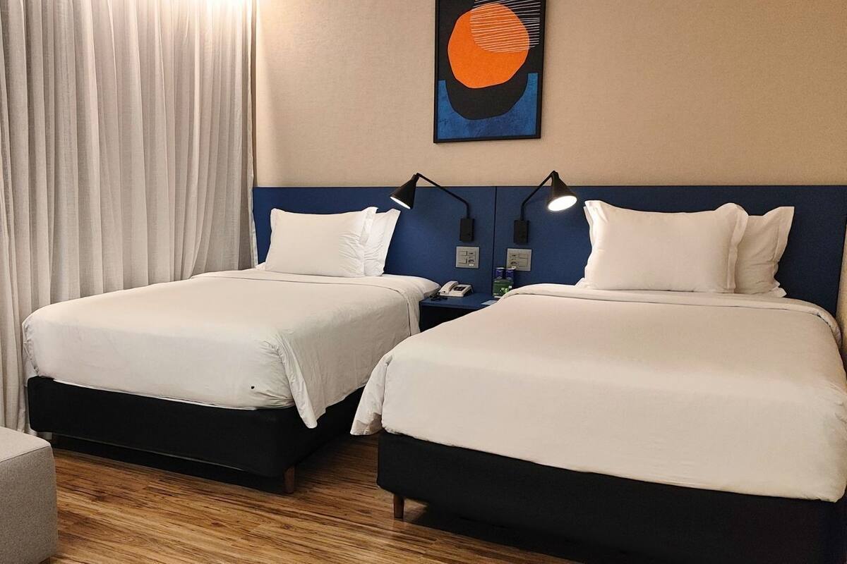 A hotel room with two beds, a sofa, and a painting on the wall.