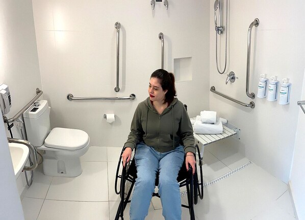 A wheelchair-accessible bathroom with a toilet, handrails, and a shower area. - Radisson Hotel Oscar Freire (São Paulo)