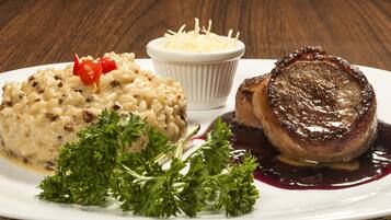 A plate with a meat dish, a side of rice, and a small bowl of cheese.