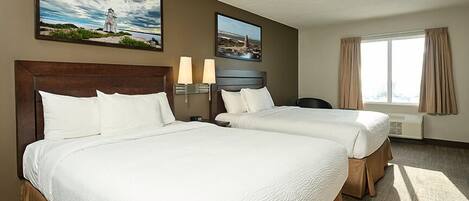 A hotel room with two beds, a desk, a chair, a window with curtains, and two wall-mounted lamps.