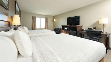 A hotel room with two beds, a desk with a computer, a TV, and a chair.