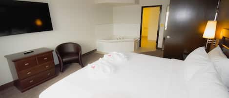 A hotel room with a bed, a TV, a desk, a chair, a bathtub, and a door.