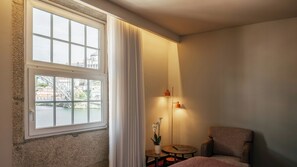 A hotel room with a large window, a sofa, a small table with a plant, and a floor lamp. - Pestana Vintage Porto Hotel & World Heritage Site (Porto)