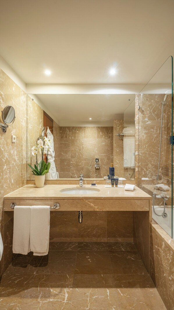 A modern bathroom with a large sink, mirror, and glass shower enclosure.