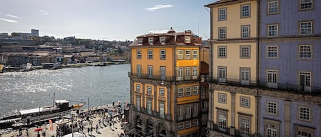 A riverside promenade with historic buildings, a dock, and people walking.