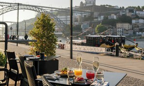 A table with breakfast items and drinks, overlooking a river with boats and a bridge. - Pestana Vintage Porto Hotel & World Heritage Site (Porto)