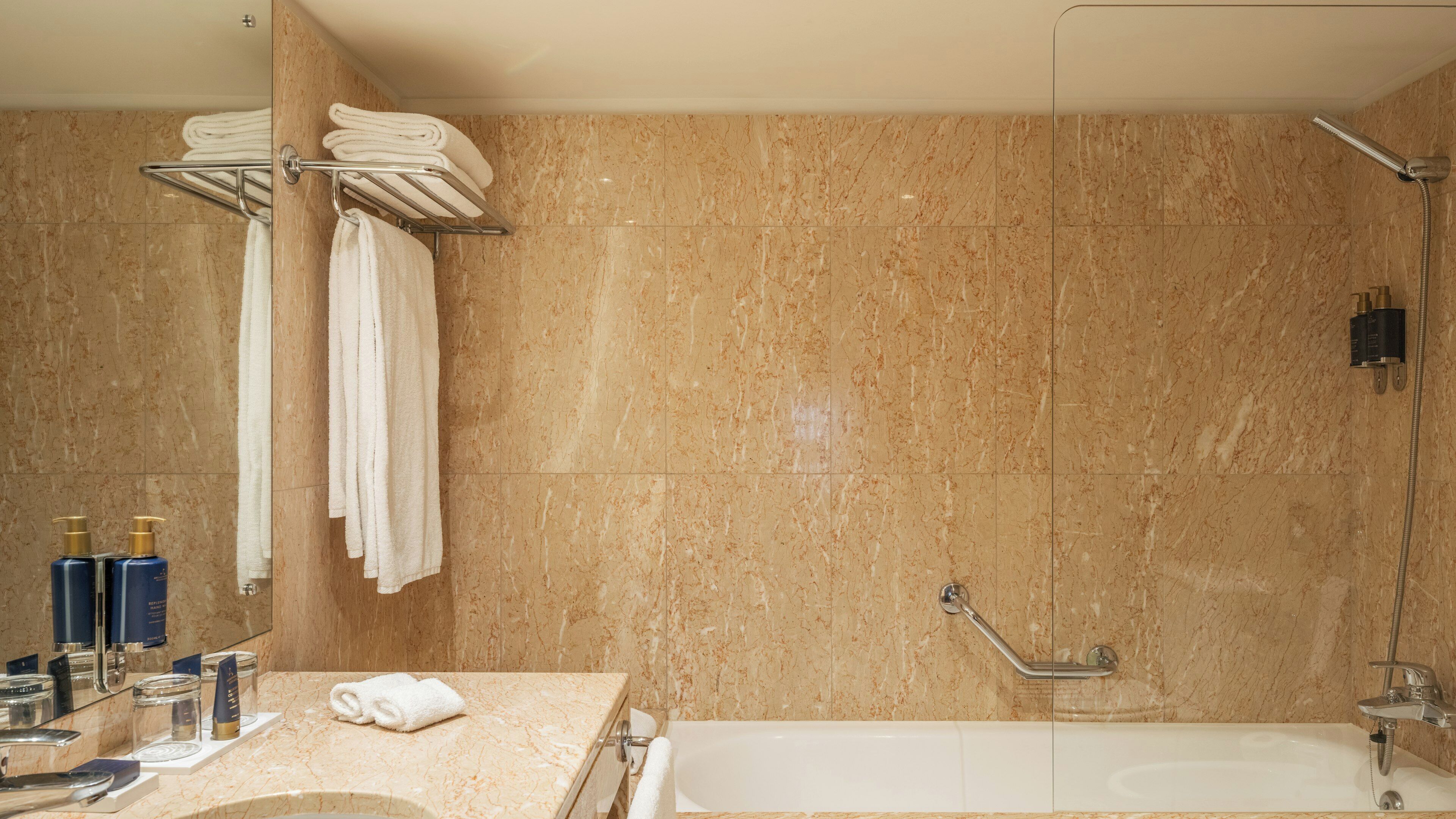 A bathroom with a bathtub, a shower, and a towel rack with folded towels.