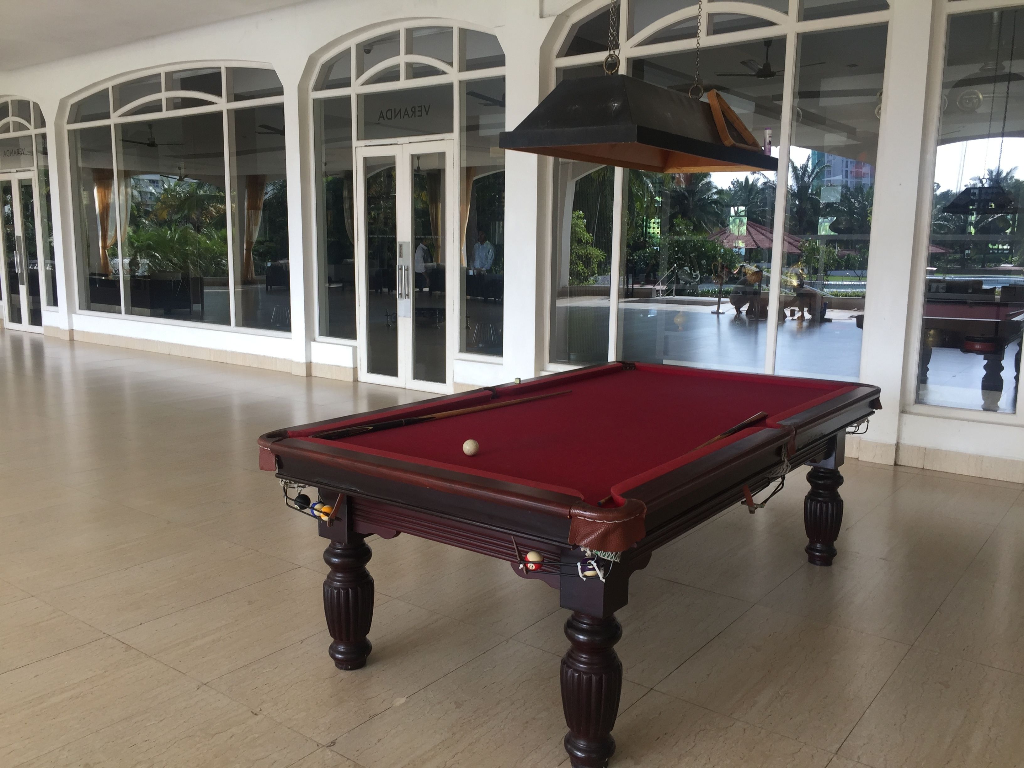 Una mesa de billar en un espacio interior amplio con ventanas grandes y arcos.