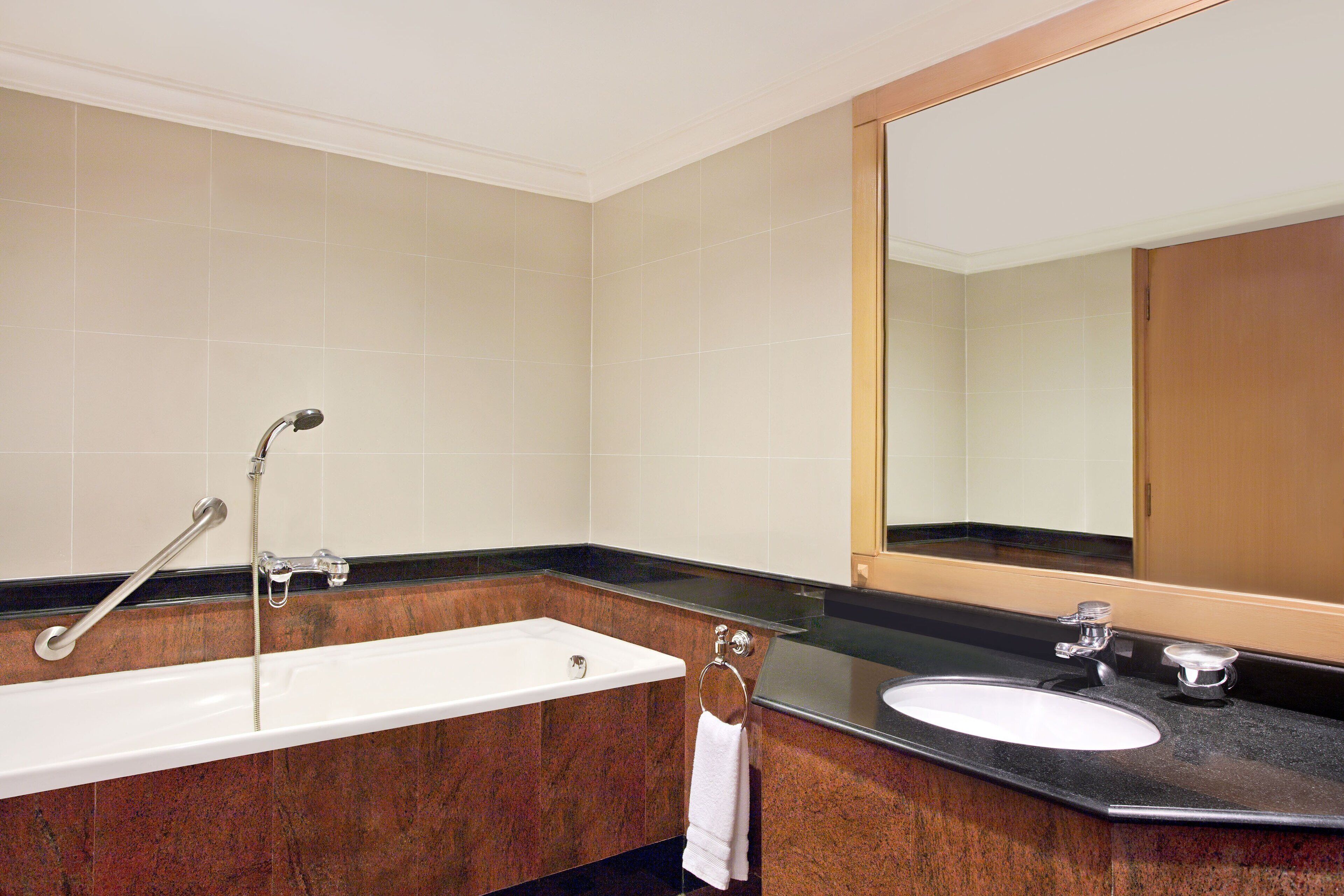 A bathroom with a bathtub, a sink, and a large mirror.
