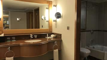 A bathroom with a large mirror, two sinks, a toilet, and a glass-enclosed shower.
