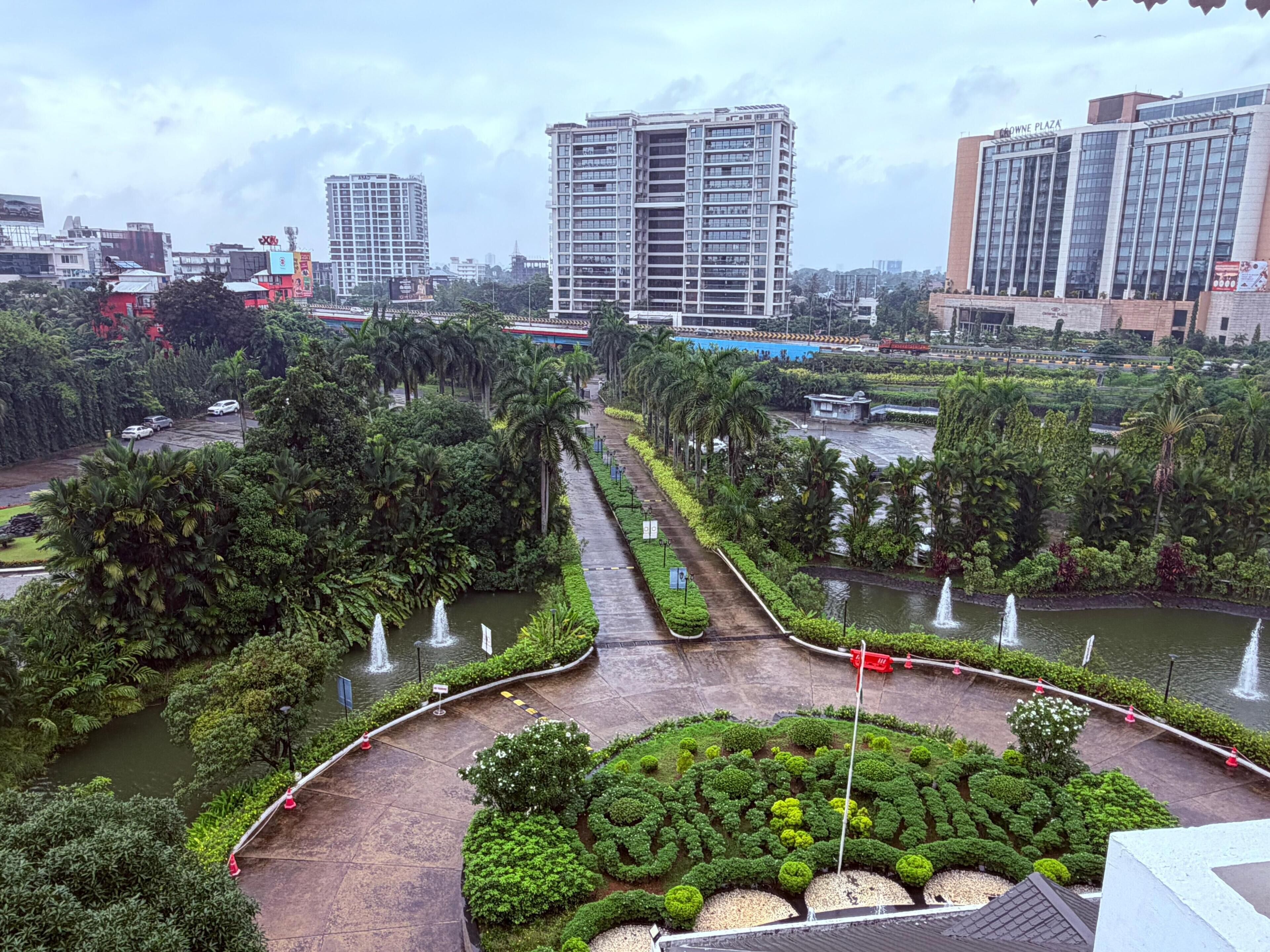 A landscaped area with a fountain, palm trees, and a pathway leading to a building labeled 'Gowne Plaza.'