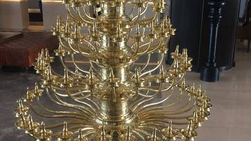 A chandelier with multiple arms and candle-like lights, mounted on a wooden base.