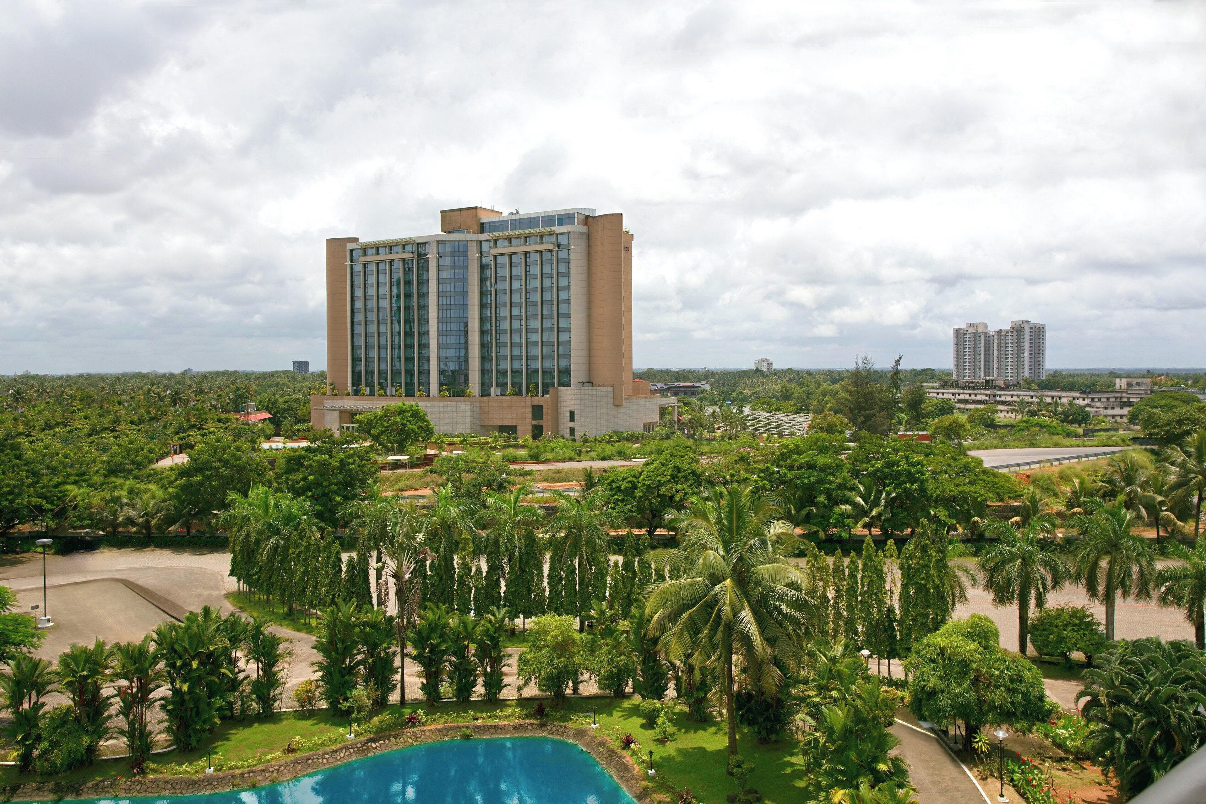 A modern hotel with a large pool surrounded by lush greenery and palm trees.