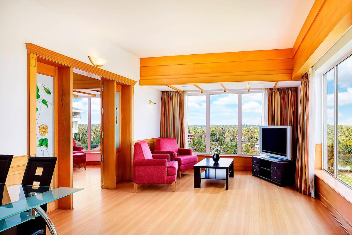 A modern living room with a TV, red armchairs, and a glass coffee table.