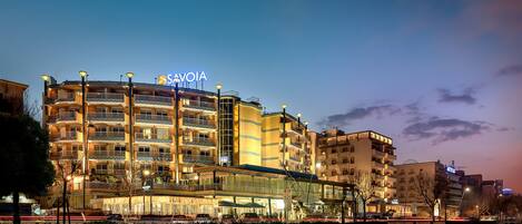A multi-story hotel with balconies, a prominent sign, and a parking area in the foreground.