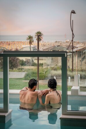 A couple in a private pool with a view of a beach and cityscape. - Savoia Hotel Rimini (Rimini)