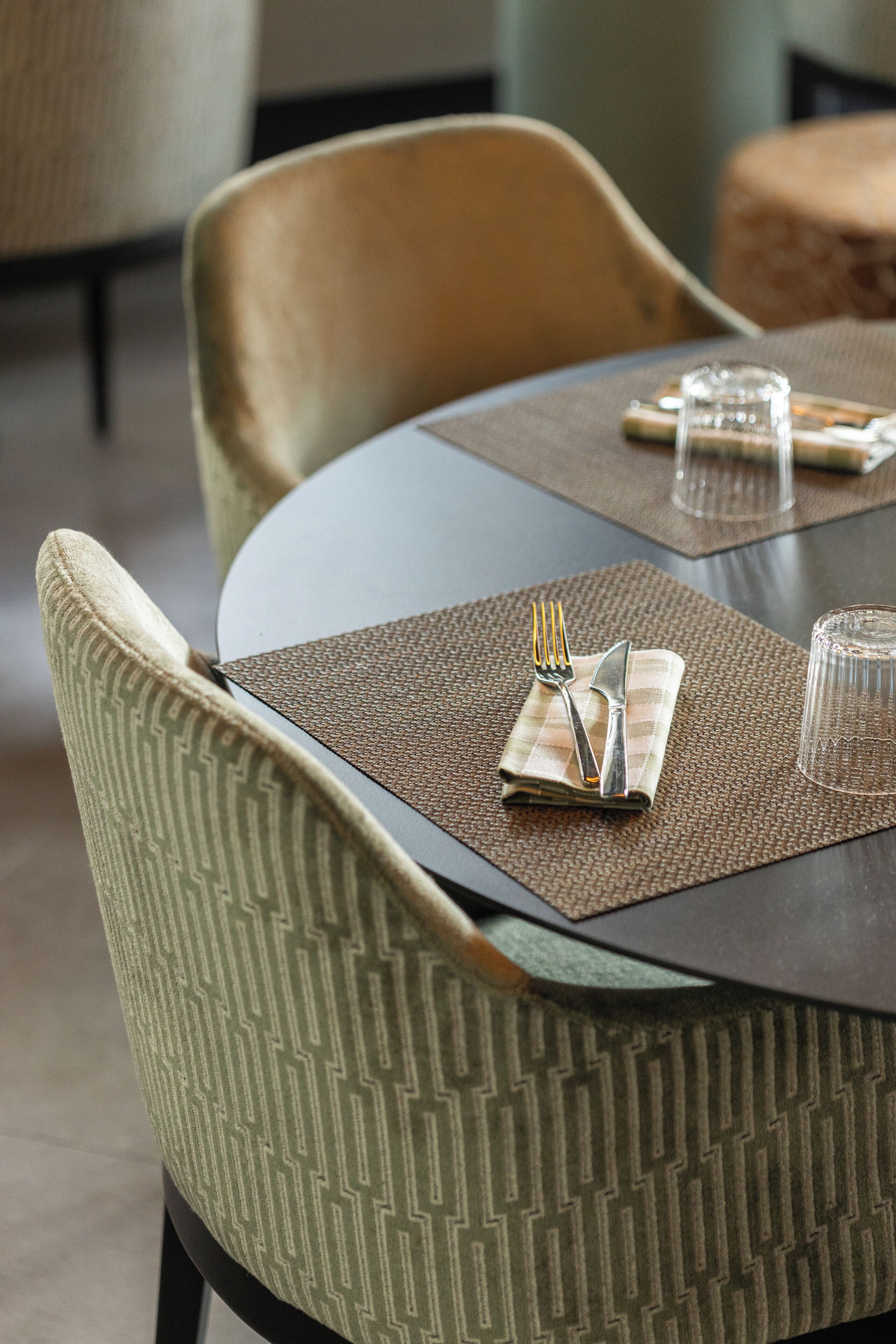 A dining table with a placemat, a folded napkin, a fork, and a knife.