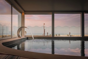 Una piscina interna moderna con vista sulla spiaggia e sull'oceano.