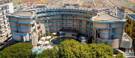 A hotel with a curved architecture, a pool, and a beach view.