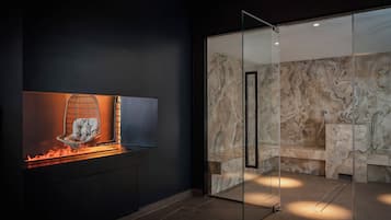 A modern bathroom with a glass shower enclosure, a marble backsplash, and a built-in sink.