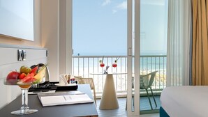 A hotel room with a balcony, a dining table with a fruit bowl and drinks, and a bed.