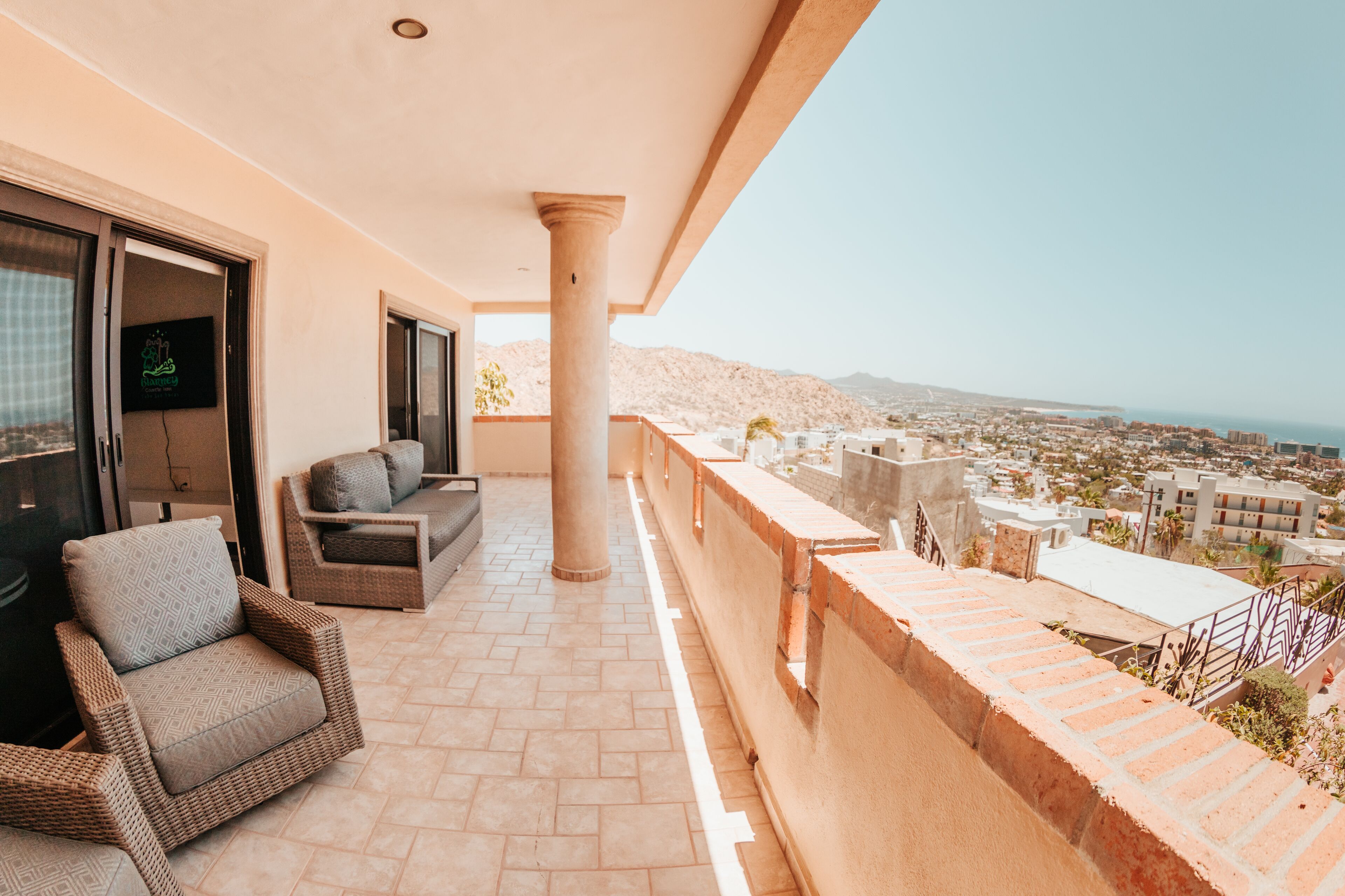 A balcony with wicker furniture, a large pillar, and a city view.