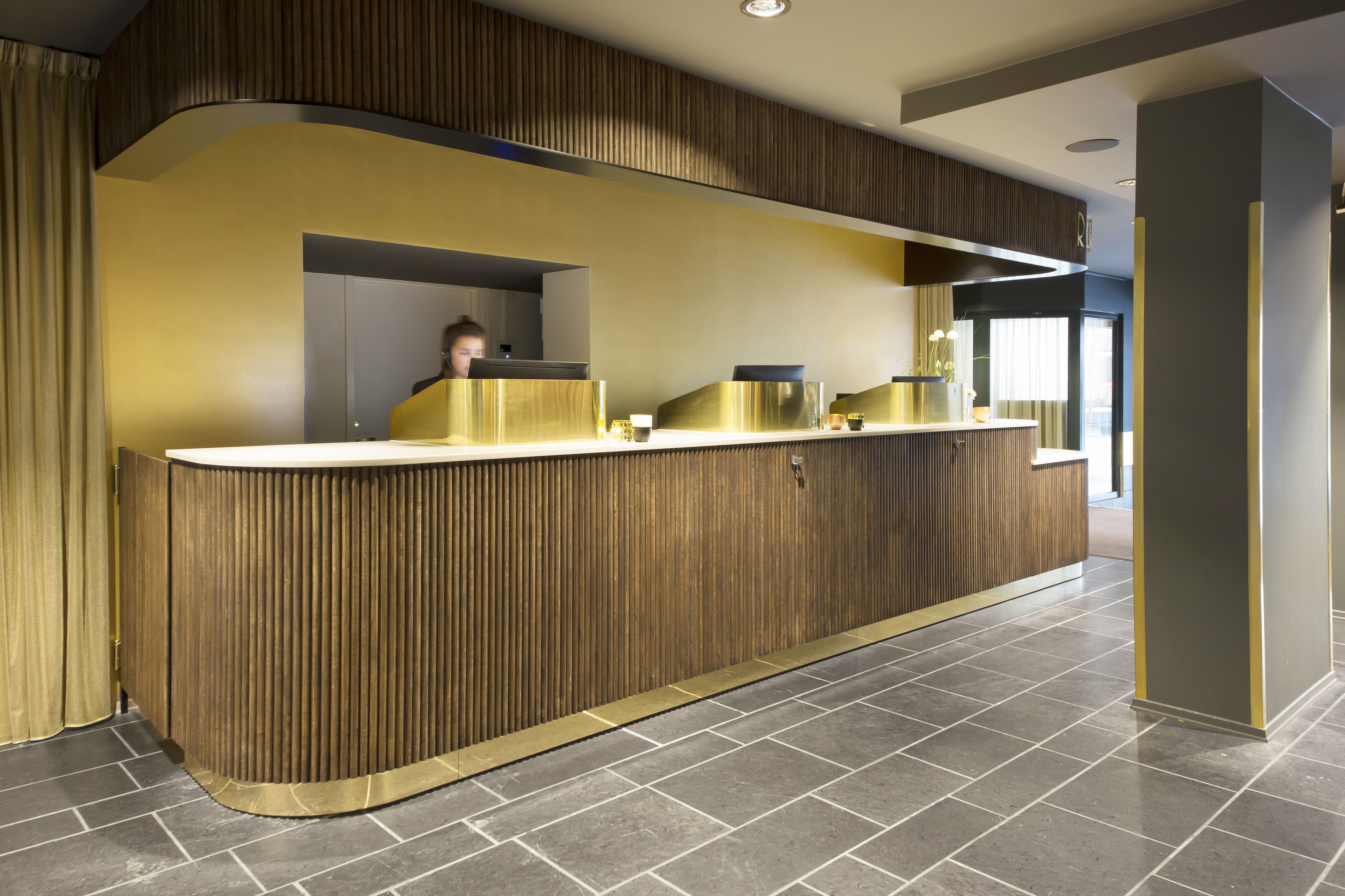 Un comptoir d’accueil avec un revêtement en bois et un design incurvé, un sol carrelé et un aménagement intérieur moderne.