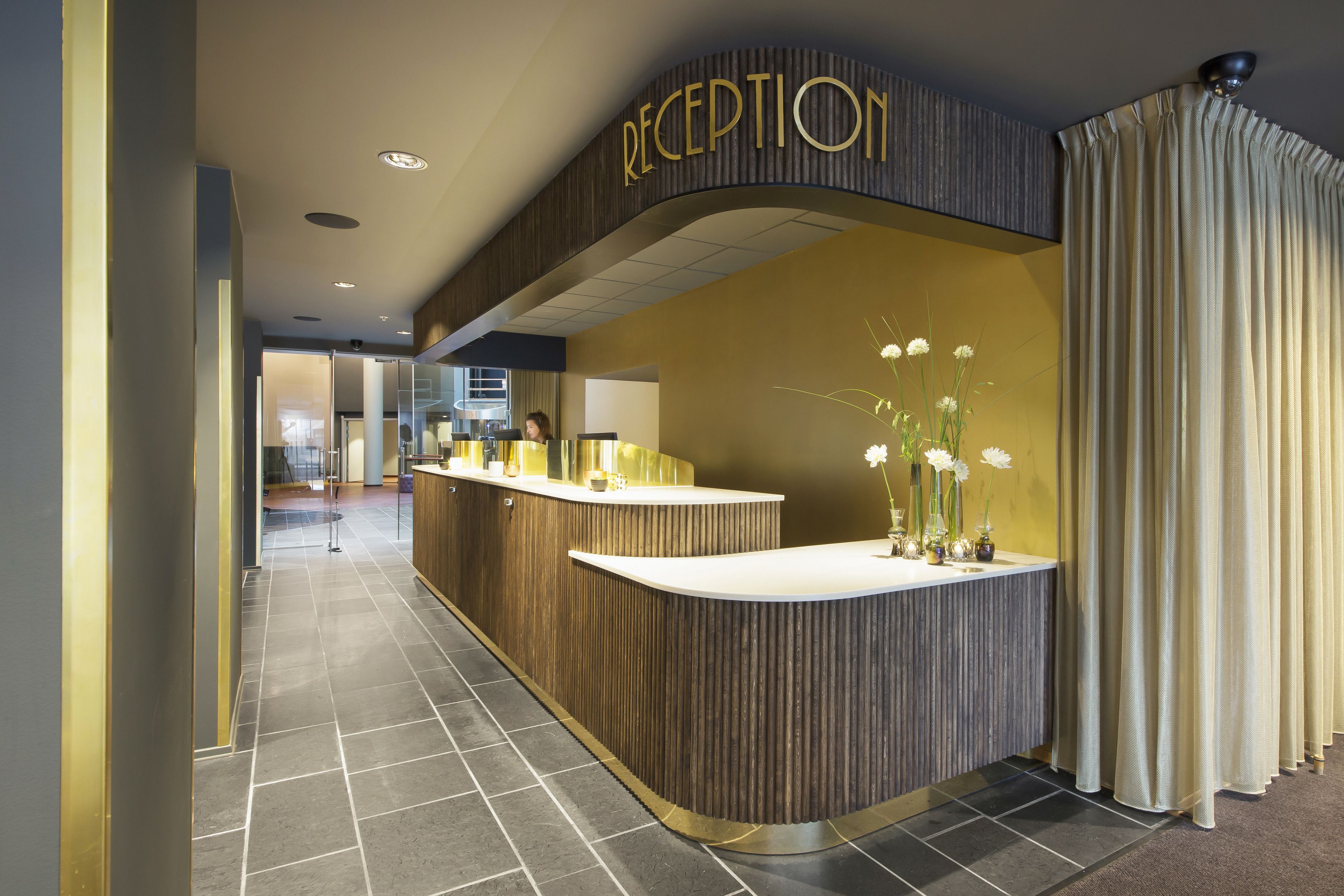 A reception area with a curved reception desk, a sign above it, and a curtain to the right.