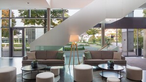 A modern interior with two sofas, multiple round tables, and a lamp.