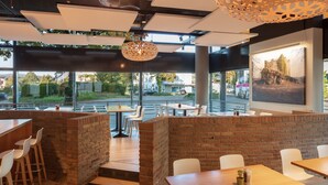 A modern restaurant with brick accents, wooden tables, and white chairs.