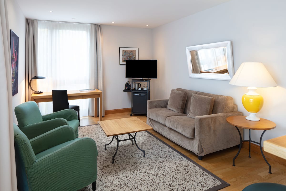 Una sala de estar moderna con un sofá, una mesa de centro, un televisor y una lámpara.