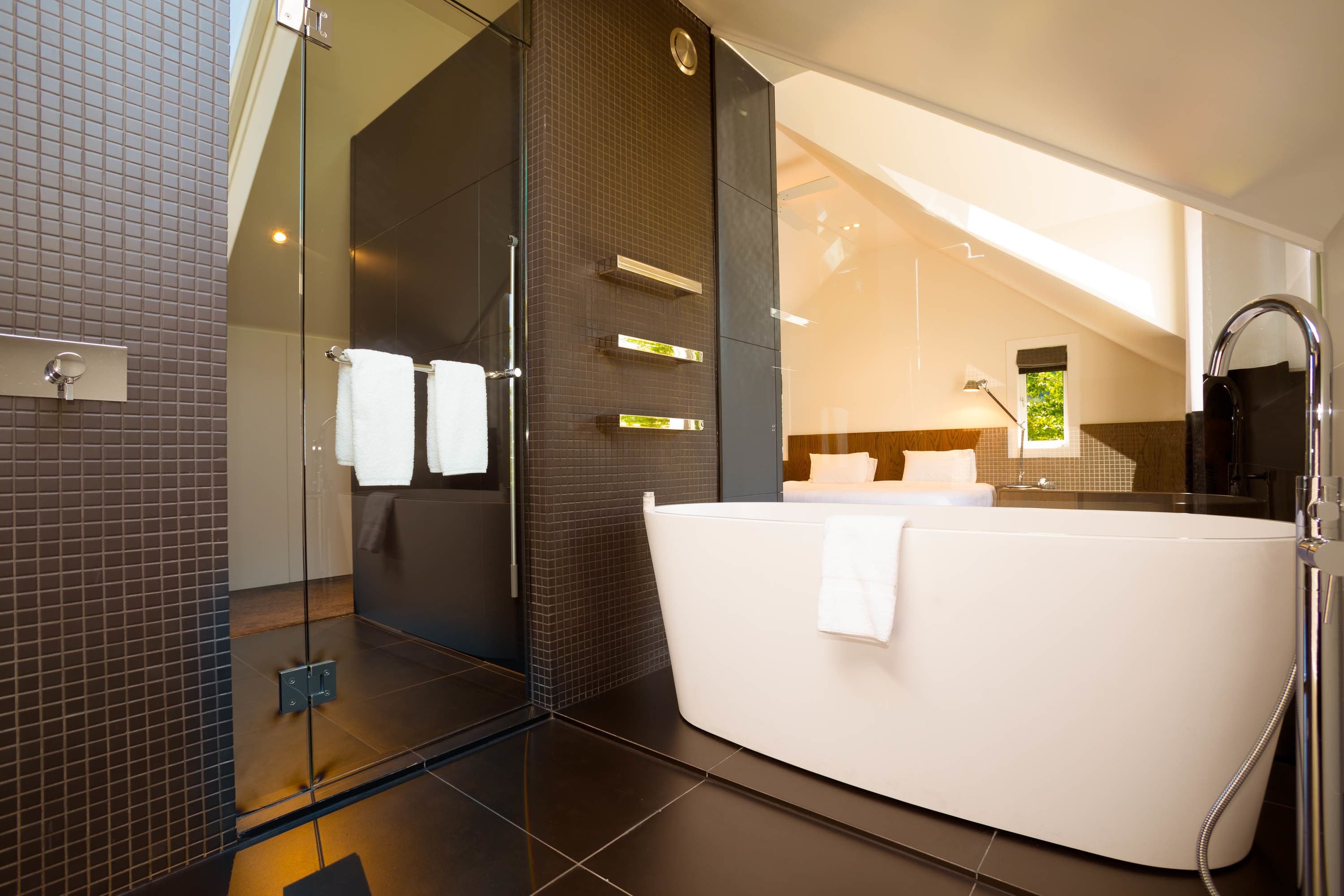 A modern bathroom with a glass-enclosed shower, a white bathtub, and a large mirror.
